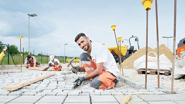 Foto eines Bauarbeiter, der einen Weg pflastert