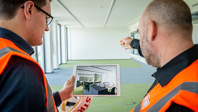 Photo of two construction workers planning a building installation