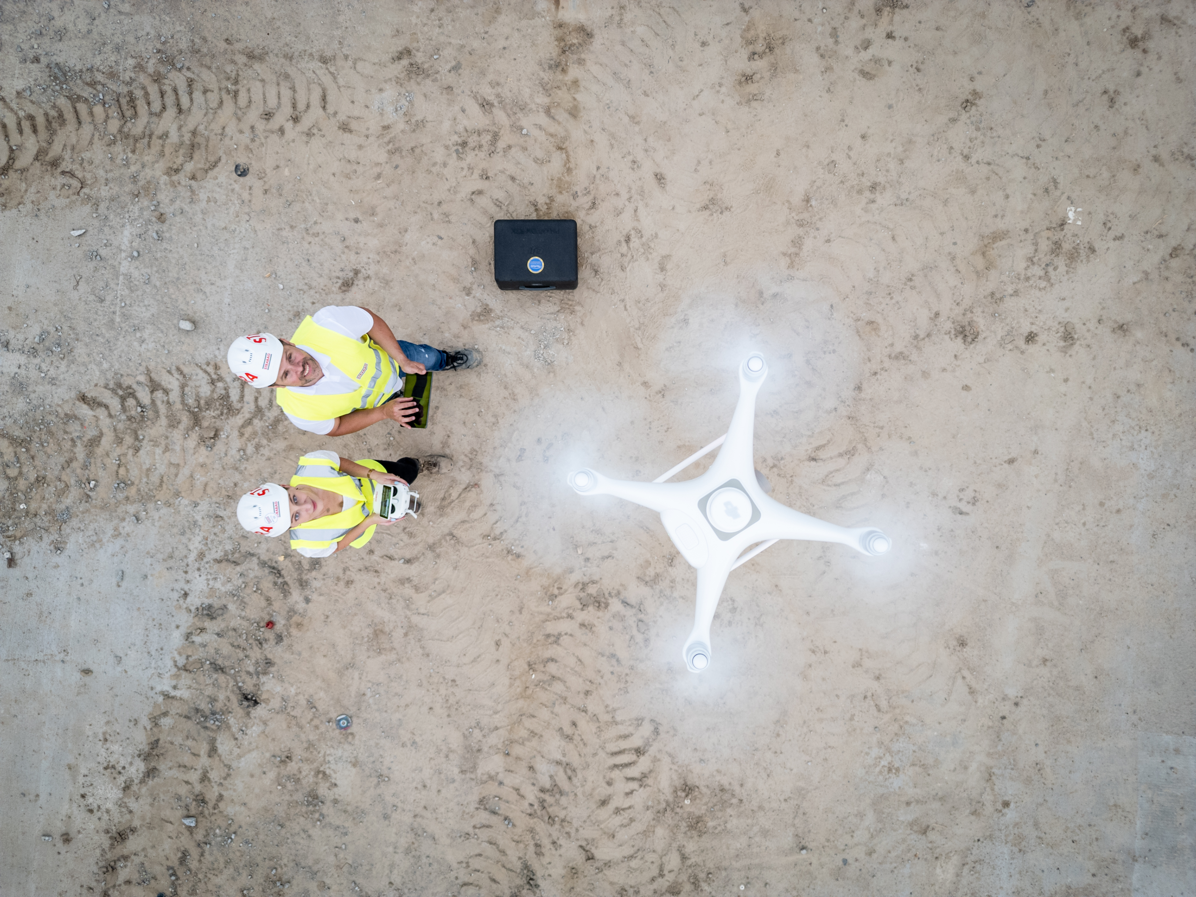 Bird's eye view of two construction workers controlling a drone