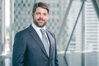 Photo of CEO Klemens Haselsteiner in front of a glass front of the STRABAG building