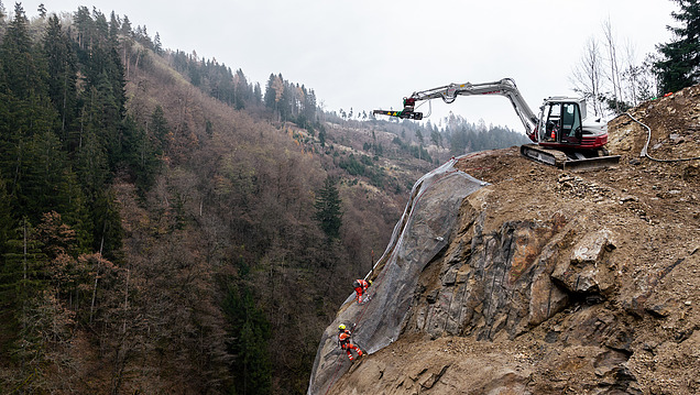 Foto einer Felshangs auf dem Bauarbeiter:innen arbeiten