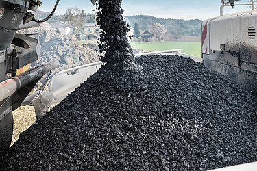 Photo shows asphalt as a raw material being unloaded at a construction site