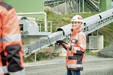 Foto von zwei Bauarbeitern, die miteinander sprechen. Einer trägt einen speziellen Turban-Helm