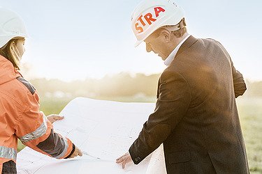 Foto von zwei Bauarbeitern, die sich einen Bauplan anschauen