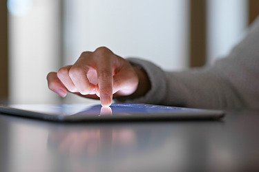 Photo of a hand typing on a tablet