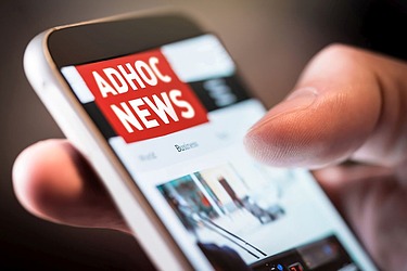 Mann scrollt auf Smartphone, wo adhoc News aufscheinen 