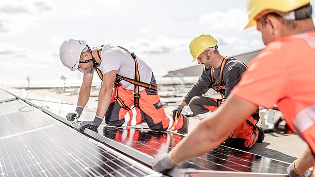 Foto einer Gruppe von Bauarbeiten, die Photovoltaikplatten montieren