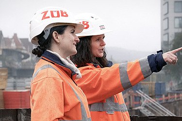 Foto von zwei Bauarbeiterinnen, die in die Ferne blicken