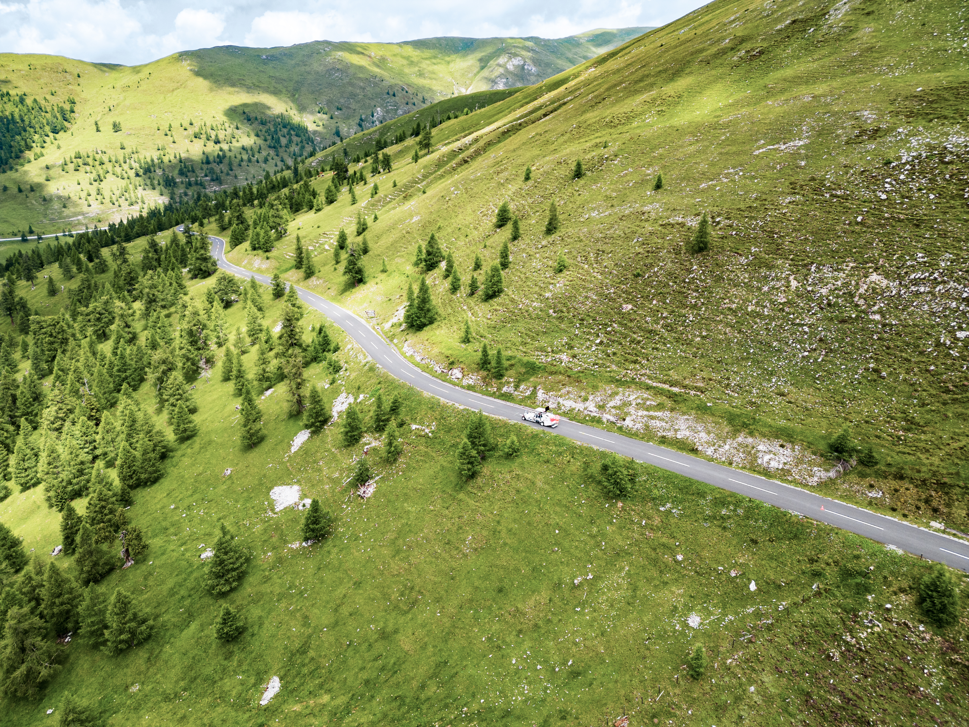 Foto von einer Straße die durch einen grünen Berg verläuft