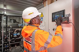 Photo of a STRABAG environmental technician checking the environmental and energy data of a building system